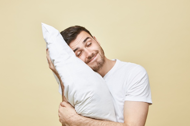 horizontal-image-handsome-cute-young-man-with-bristle-posing-with-head-white-soft-pillow-sleeping-peacefully-smiling-seeling-good-dream-attractive-guy-napping-after-hard-working-day_343059