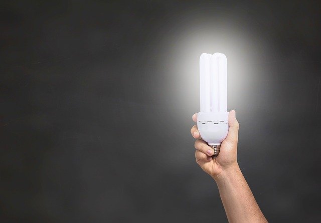 Človek drží v ruke zapálenú podlhovastú žiarovku.jpg